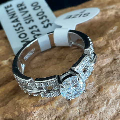 Silver ring with diamond on a stone surface with a price tag.