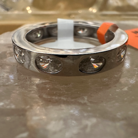Silver ring with embedded stones on a reflective surface