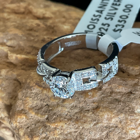 Silver ring with gemstone on a rock with a price tag.