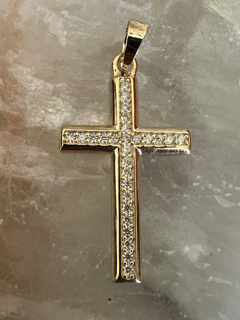 Gold cross pendant with diamonds on a marble surface