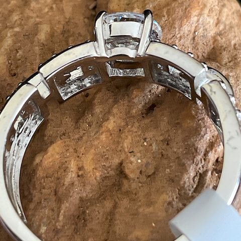 Silver ring with diamond accents on a stone surface