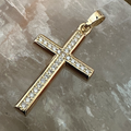 Gold cross pendant with diamonds on a marble surface