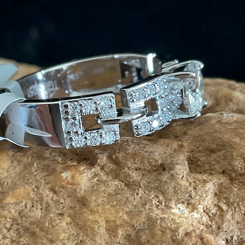 Silver ring with diamond accents on a stone surface