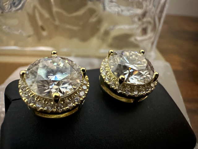 Gold and crystal earrings on a black stand with a blurred background