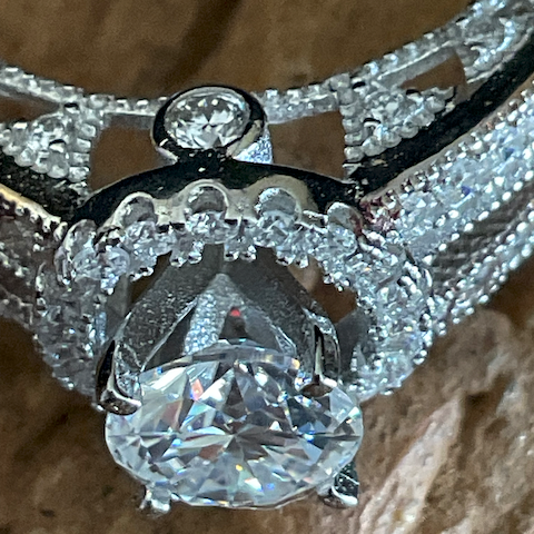 Close-up of a diamond ring with a textured band on a stone surface