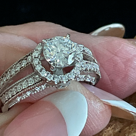 Close-up of a diamond ring on a finger with a blurred background