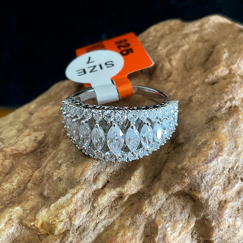 Silver ring with clear gemstones on a rock, size 7 tag visible