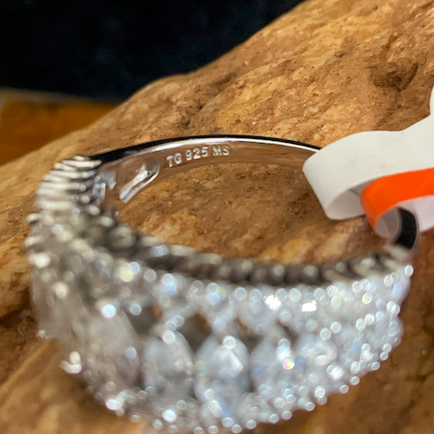 Silver beaded bracelet on a wooden surface with '925' stamp