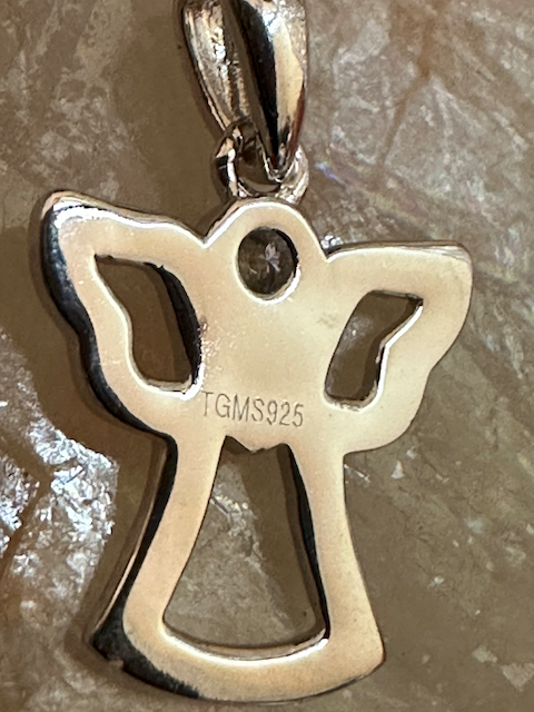 Silver angel pendant with 'TGMS925' marking on a textured surface
