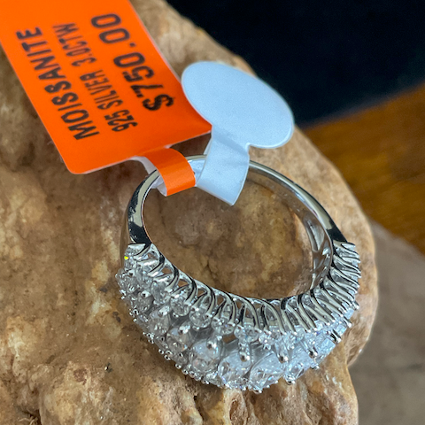 Silver ring with gemstones on a rock, price tag visible