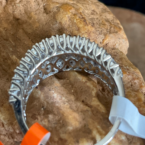 Silver ring with intricate design on a rock background