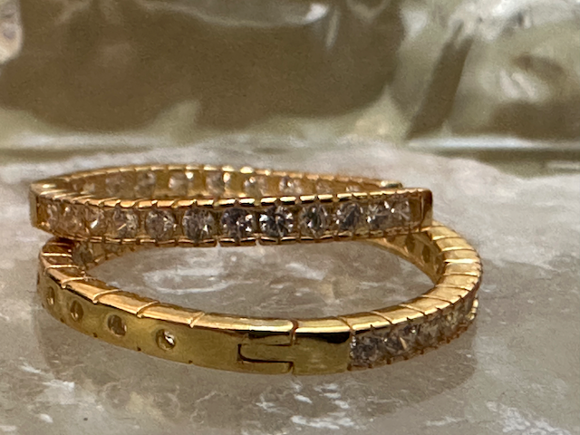 Two rosegold earrings with diamond accents on a reflective surface