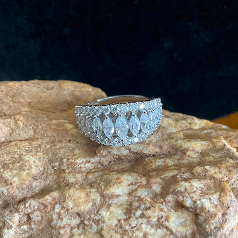 Silver ring with intricate design on a textured stone surface