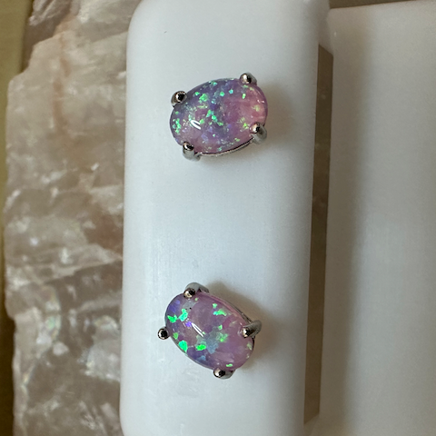Opal earrings on a white stand with a blurred background