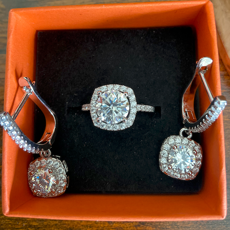Silver jewelry set with earrings and a ring in an orange box on a wooden surface