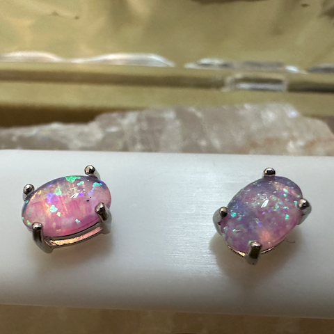 Pair of pink gemstone earrings on a white stand with a blurred background