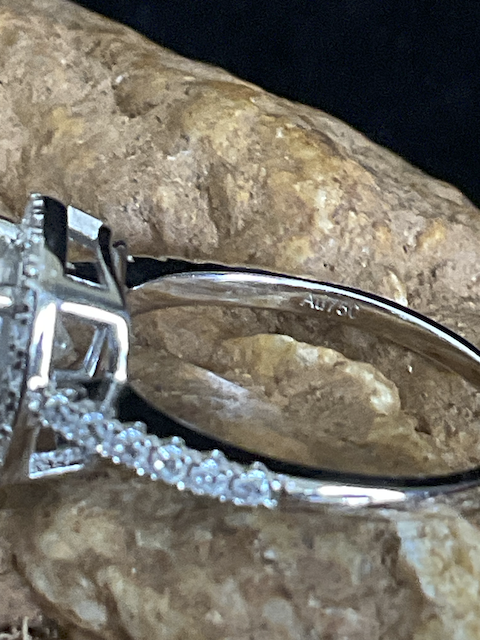 Silver ring with diamond accents on a textured stone surface