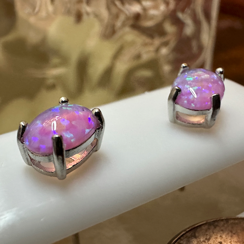 Pair of silver earrings with purple gemstones on a white surface.