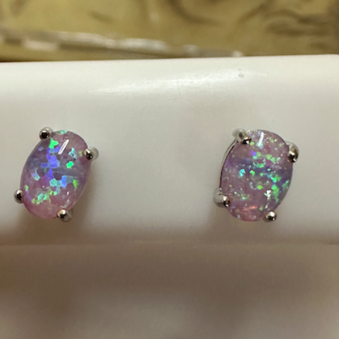Pair of earrings with iridescent stones on a white stand.