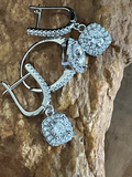 Silver earrings with clear gemstones on a textured stone background