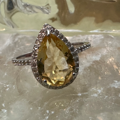 Ring with a large yellow gemstone and smaller diamonds on a textured surface