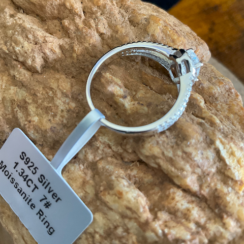 Silver ring with moissanite on a rock, labeled as 925 silver.