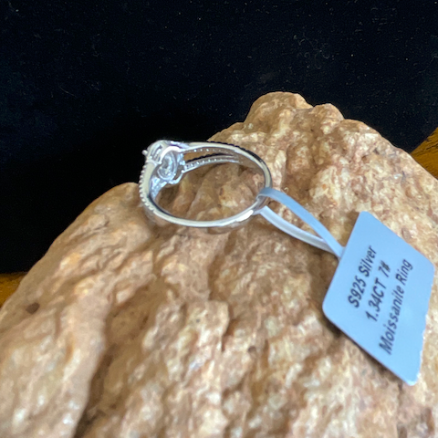 Silver ring on a rock with a tag indicating '925 Silver' and '14Kt Gold'.