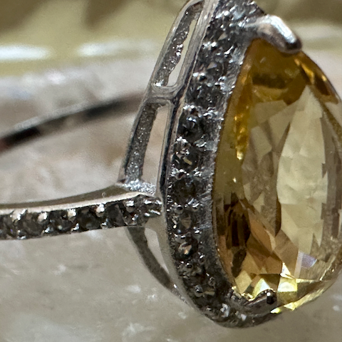 Silver ring with a large yellow gemstone on a light background