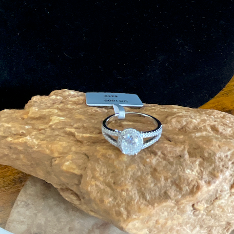 Silver ring with a diamond on a rock against a black background
