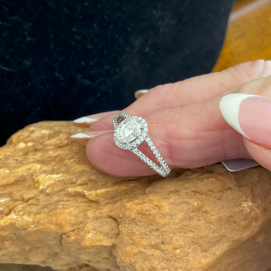 Silver ring with a diamond on a finger against a textured background