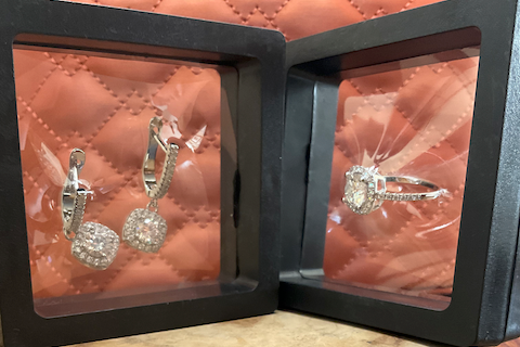 Jewelry set including earrings and a ring in a black display case on a wooden surface.