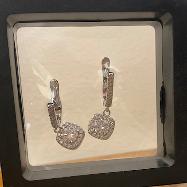 Heart-shaped earrings in a black box on a wooden surface