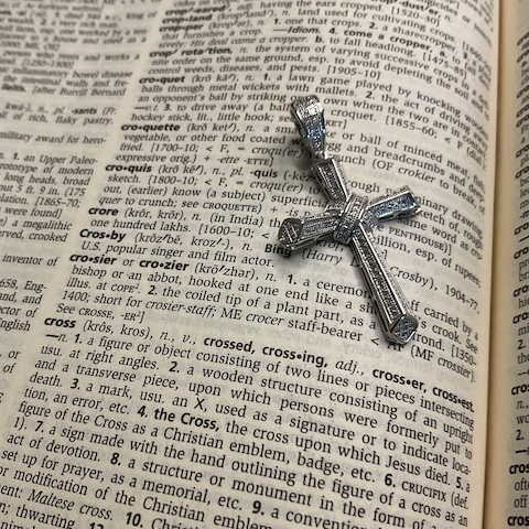 Silver cross pendant on an open dictionary page