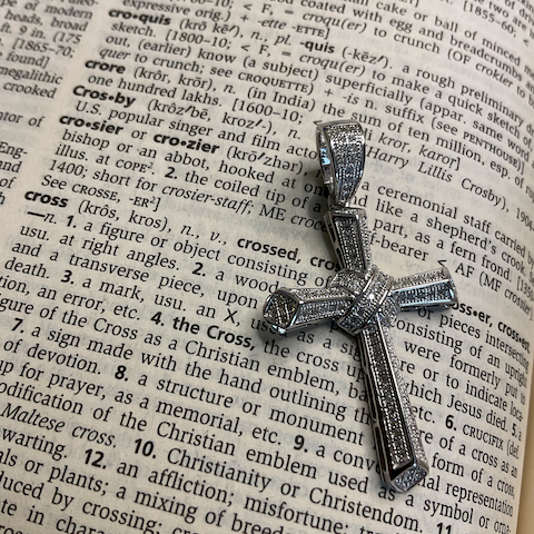 Silver cross pendant on an open dictionary page
