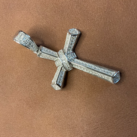Silver cross pendant on a brown background