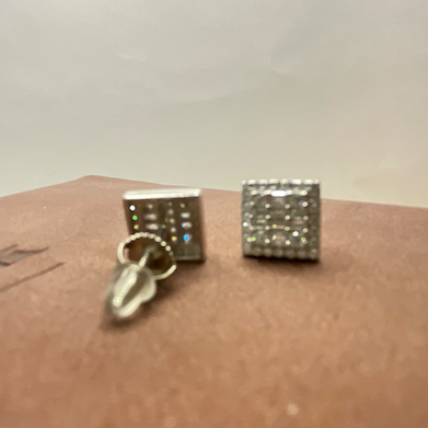 Two silver square-shaped earrings on a brown surface.