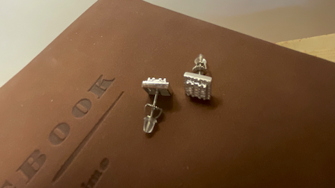 Silver earrings on a brown surface with a blurred background