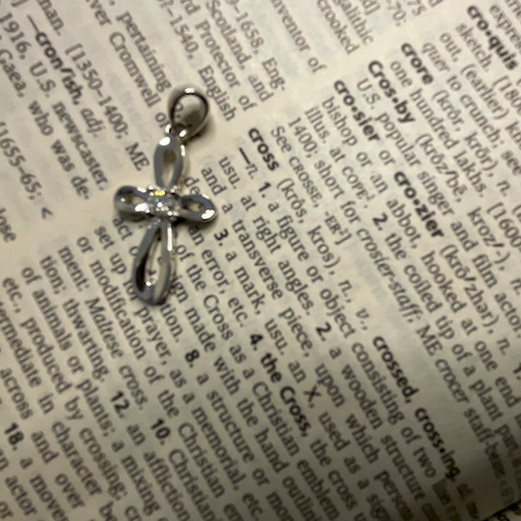 Silver bow-shaped pendant on a piece of paper with printed text