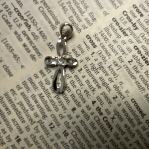 Silver bow-shaped pendant on a dictionary page