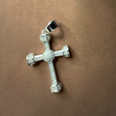 Silver cross pendant on a brown background