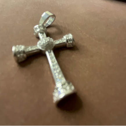 Silver cross pendant on a textured surface with 'The Second Summer' text in the background.