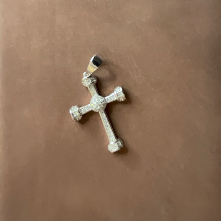 Silver cross pendant on a brown surface