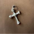 Silver cross pendant on a brown surface
