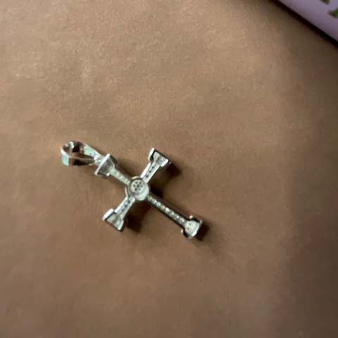Silver cross pendant on a brown surface