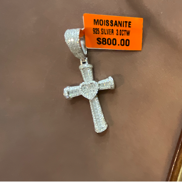 Silver pendent with orange tag on a brown surface