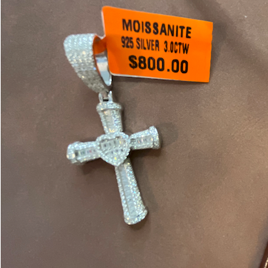 Diamond cross pendant with orange tag on a brown surface