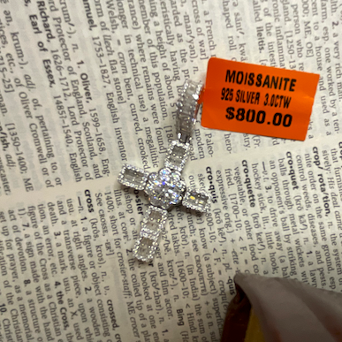 Silver cross pendant with a price tag on a newspaper background