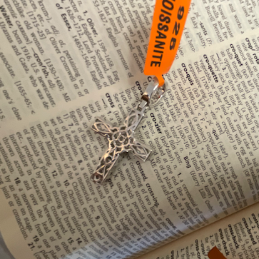 Silver pendant on a printed paper with a visible brand tag.