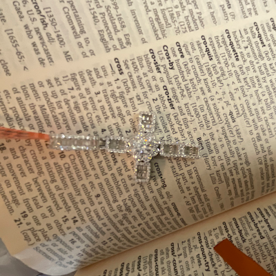 Silver flower-cross charm on an open book