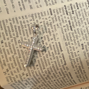 Open book with a star-shaped pendant on a page, held open by a hand holding a phone.